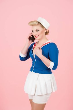 Anime tarzı kadın akıllı telefon üzerinde gül arka plan üzerinde konuşuyor. Çekici genç denizci kız sarışın kıvrılma ve pin-up makyaj ile cep iletişim