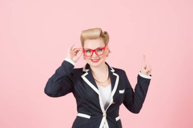 Mavi ceket göstermek yerine yukarıdaki sarışın pin-up kızı. Kadın ceket ile kırmızı gözlük ve büyük parmak tarafından yukarı nokta gülümse. Kadın reklam alanı yapar ve gözlük ile el düşünün