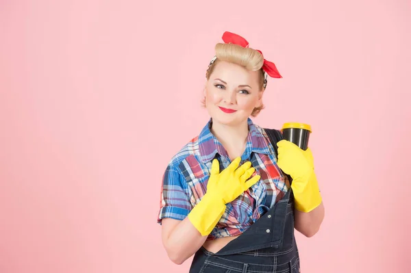 gratefulness housewife holding craft cup. Portrait of thankfulness woman in rubber gloves with cup of coffee in pin-up style. Blonde girl thanks for the love isolated on pink background