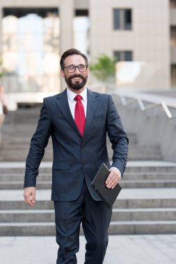 işadamı tablet ile el bina ofiste duruyor. iş takım elbise ve beyaz gömlek giymiş insanın yapacağı işleri mutlu ve başarılı bir şekilde tablet ile