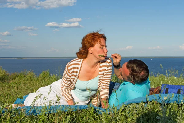 birlikte yaz çim üzerinde nehir kıyısında mavi gökyüzü ve bulutlar altında çim üzerinde yalan çift rahat giyinmiş