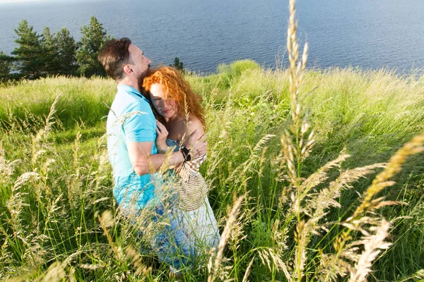 büyük yeşil çim sarılma aşık genç bir çift. İki aşık tutkuyla sarılma. Uzun zamandır beklenen toplantı alanında göl veya nehir iki aşıkların.