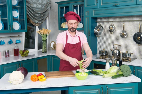 Young Man Cooking in the kitchen. Healthy Food - Vegetable Salad. Vegan Diet. Vegan Dieting Concept. Healthy Lifestyle. Cooking At Home. Man Prepare Food