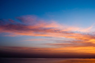 Okyanus üzerinde mavi gökyüzünde kırmızı güneş doğuyor. Sabah erken mavi gökyüzünde bulutlar sabah ile deniz. Sunrise mavi gökyüzü ve soğuk su.