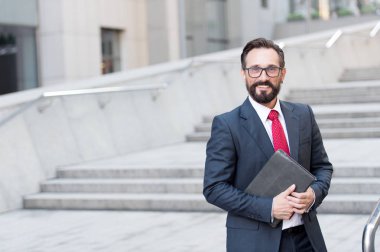 Karanlık şık elbiseli açık havada onun elinde modern bir aygıt ile ayakta ve gülümseyen hevesli olumlu avukat