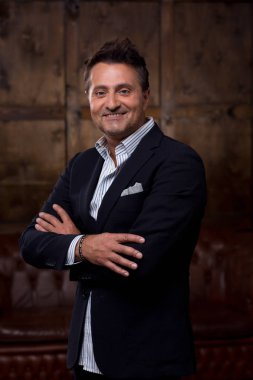 Şık elbise giyiyor ve duran kollarını ile gülümseyen emin orta yaşlı işadamı geçti