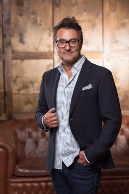 Sakin yakışıklı orta yaşlı işadamı kapalı tek başına ayakta ve tek elle ceket sana bakarken gülümseyen zarif giysiler