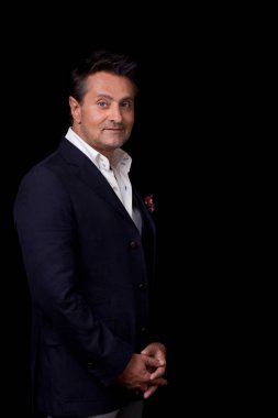 Sakin meraklı orta yaşlı işadamı şık giysileriyle siyah arka plan karşı dururken gülümseyen