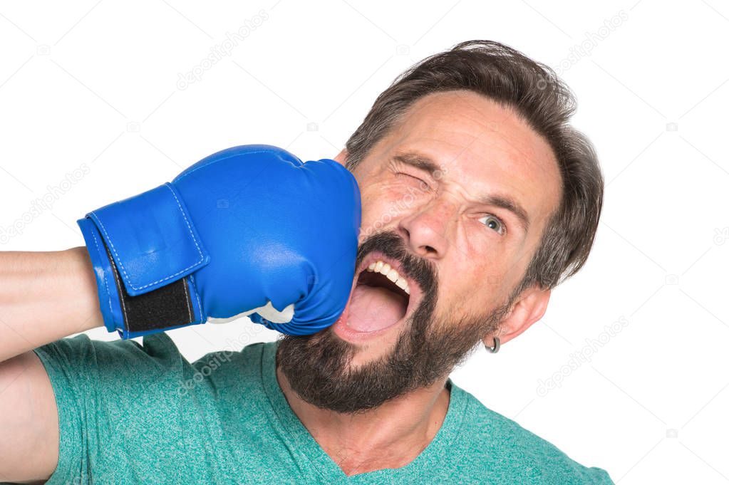 Ouch. Bearded mature boxer screaming in pain while hitting himself with blue boxing glove and experiencing defeat