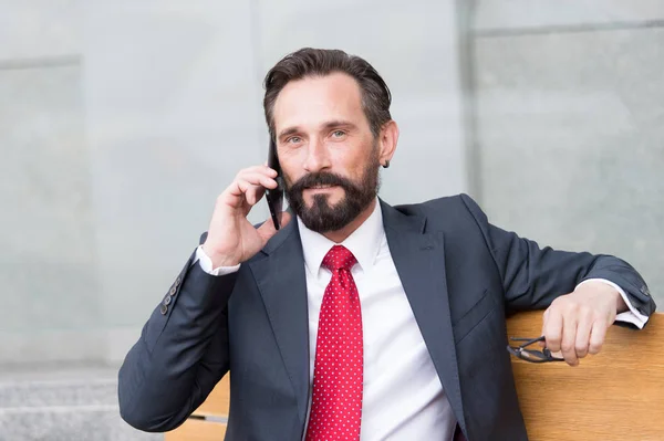 Karizmatikus áttekintése, sikeres üzletember beszél telefonon, szabadban, glasess a kézben — Stock Fotó