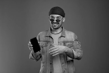 Keyifli adam, günlük giysiler içinde akıllı telefonuyla başka tarafa bakıyor.