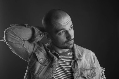 Kolu başının arkasında olan sakin ve yakışıklı bir adamın düşünceli bakışı.