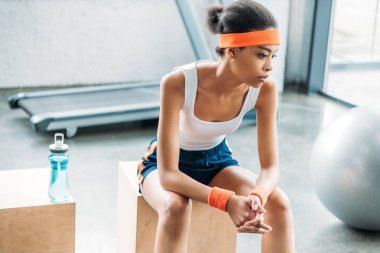 çekici Afro-Amerikan sporcumuz kafa bandı ve spor salonunda ahşap kutu üzerinde saç bantları