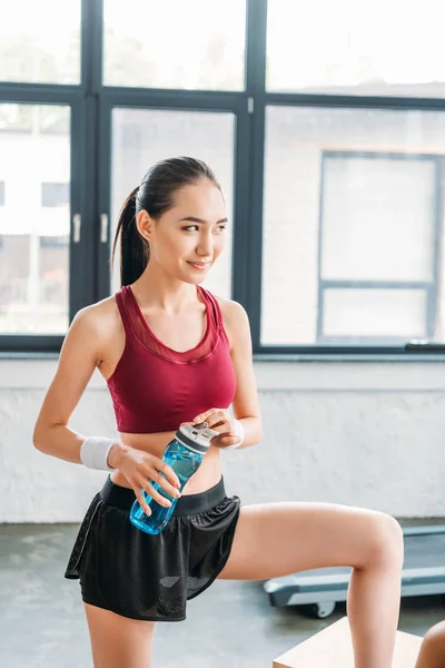 Χαμογελώντας Ασίας Αθλήτρια Μπουκάλι Νερό Στο Γυμναστήριο — Δωρεάν Φωτογραφία
