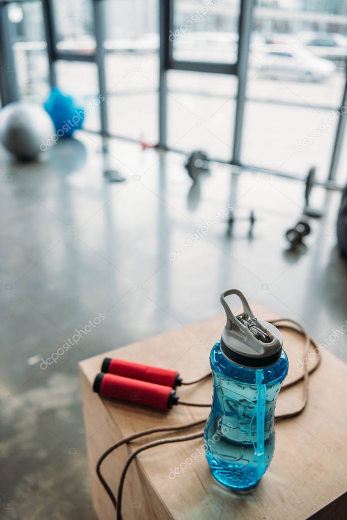 closeup view of jump rope and bottle of water on wooden box at gym