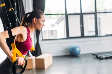 Asyalı kadın atlet spor salonunda direnç gruplarla eğitim yan görünüm