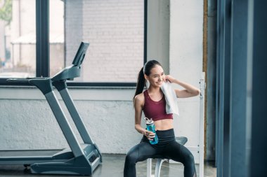 sportif su şişesi ve spor salonunda egzersiz sonra dinlenme havlu ile Asya sporcumuz gülümseyen