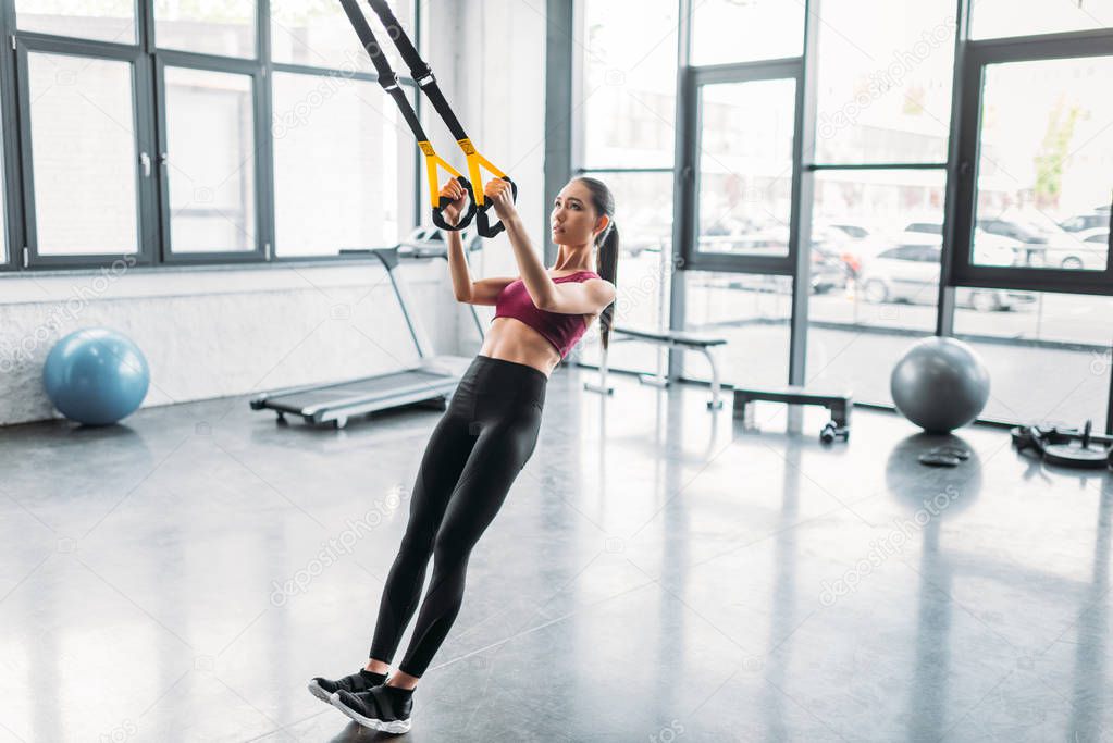 asian female athlete training with resistance bands at gym