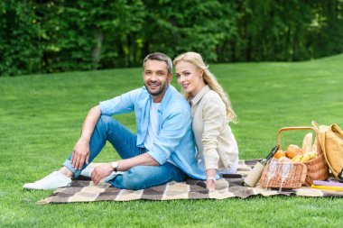 ekose üzerinde oturan ve kamera Park gülümseyen mutlu çift