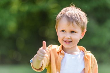 çok güzel mutlu küçük çocuk parkında başparmak gösterilmesini