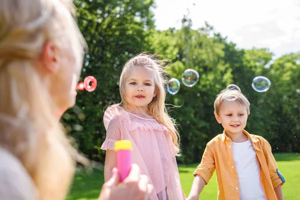 选择性聚焦母亲吹肥皂气泡 而花时间与孩子在公园 — 图库照片