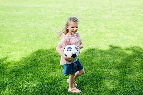 Высокий Угол Зрения Счастливого Маленького Ребенка Держащего Футбольный Мяч Траве — стоковое фото