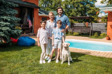 yaz günü ülke evin arka bahçesinde üzerinde ayakta iken kameraya bakarak labrador köpek ile neşeli aile
