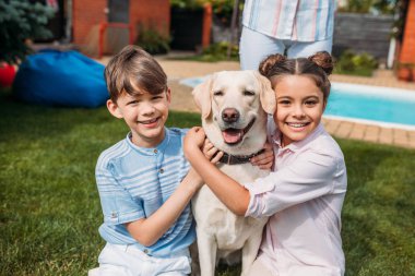 gülümseyen çocuklar Labrador köpek .arka bahçesine sarılma