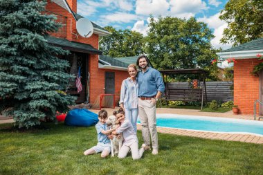 neşeli aile ile zaman ülke evin arka bahçesinde üzerinde yaz gününde harcama yaparken kameraya bakarak labrador köpek