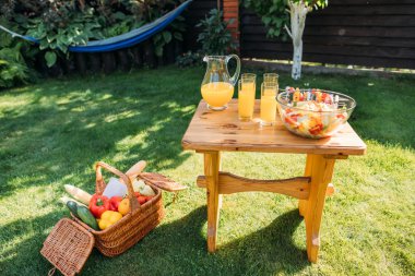 sepet piknik, gözlük suyu ve taze salata için yiyecek ve görünümü üzerinde yeşil çim üzerinde ahşap sandalye kadar kapatın