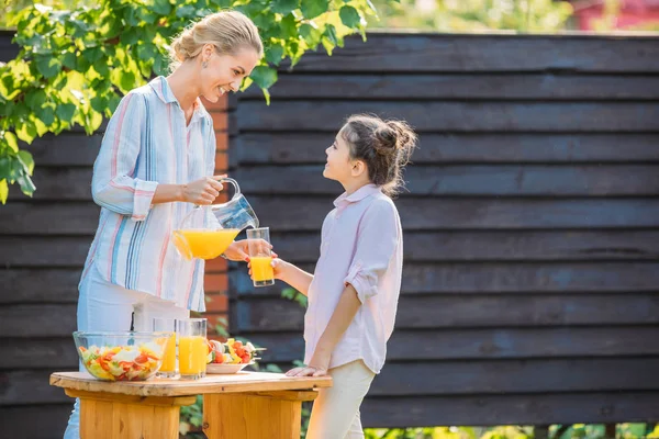 Side View Smiling Mother Pouring Juice Daughters Glass Picnic Backyard — Stock Photo, Image