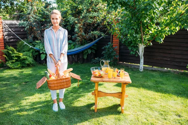 裏庭のピクニックのための新鮮な野菜がいっぱい入ったかごを持つ女性 — ストック写真