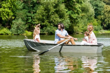 güneşli günde Park'ta Nehri üzerinde tekne sürme güzel genç aile yan görünüm