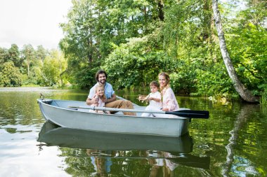 Park Nehri üzerinde tekne sürme ve kameraya bakarak Genç aile gülümseyen