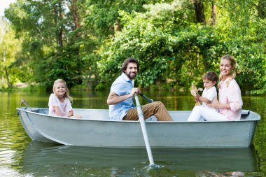 Genç aile binme teknede river Park ve kameraya bakarak gülen in yan görünüm