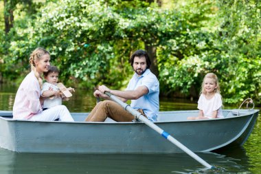 Genç aile Park'ta Nehri üzerinde tekne sürme yan görünüm