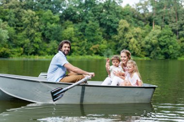 Genç aile Park'ta gölde tekne sürme yan görünüm