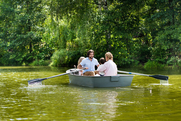 happy young family spending time together in boat on river at park