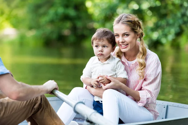 父母乘坐小船在湖与儿子在公园 — 图库照片