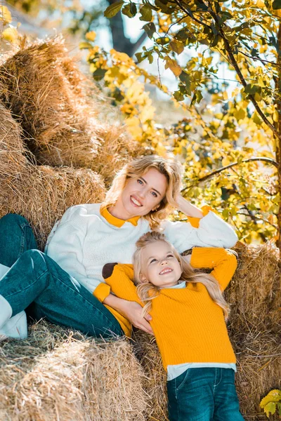 stock image smiling adult woman posing with little daughter on hay stacks at farm