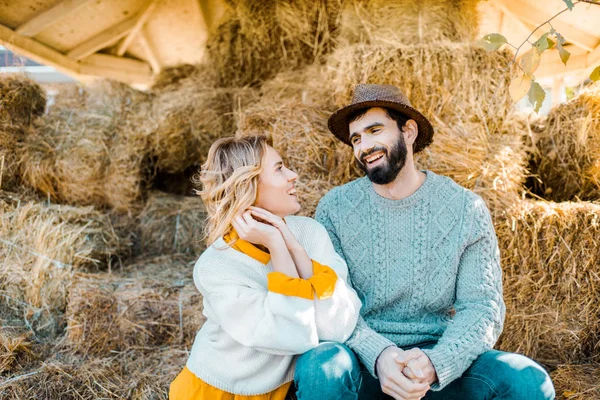 Sorridente Coppia Agricoltori Che Guardano Mentre Siedono Pile Fieno Fattoria — Foto stock gratuita