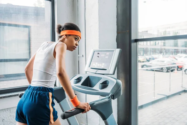 Young african american female jogger running on treadmill at gym — Stock Photo