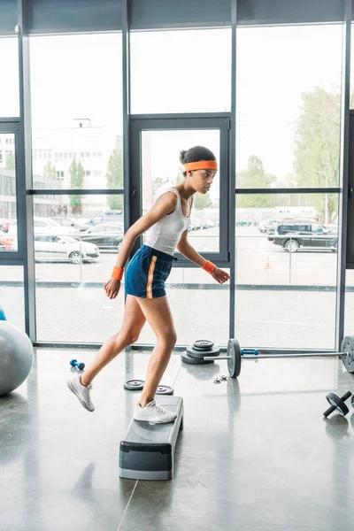 Молода афроамериканська спортсменка робить крок аеробіки в спортзалі — стокове фото