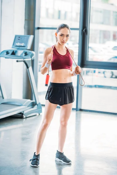 Young asian sportswoman with skipping rope looking at camera at gym — Stock Photo