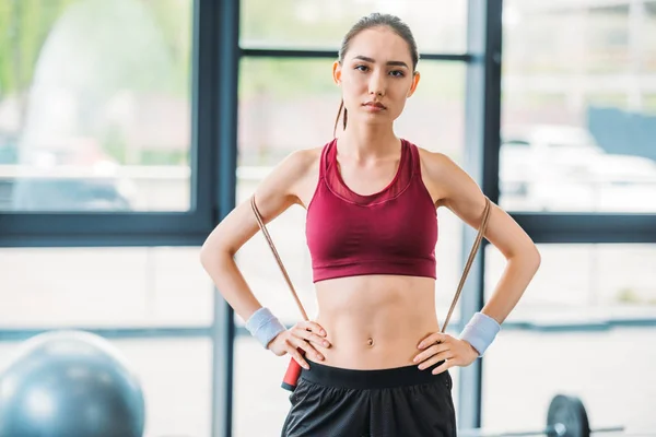 Portrait de jeune sportive asiatique avec corde sautante regardant caméra à la salle de gym — Photo de stock