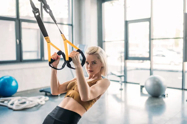 Portrait of young caucasian sportswoman training with resistance bands at gym — Stock Photo
