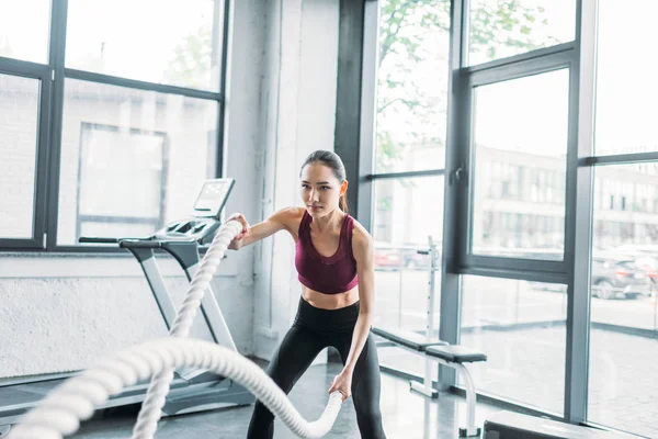 Portrait de sportive asiatique travaillant avec des cordes de combat à la salle de gym — Photo de stock