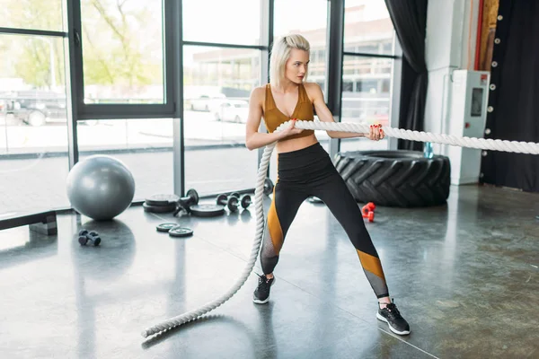 Вид збоку молодої спортсменки, що працює з бойовою мотузкою в спортзалі — стокове фото