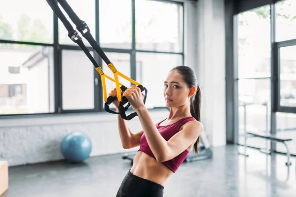 Vista laterale di asiatica atleta femminile formazione con bande di resistenza in palestra — Foto stock