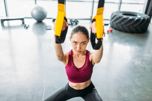 Alto ángulo vista de asiático mujer atleta entrenamiento con resistencia bandas en gimnasio - foto de stock
